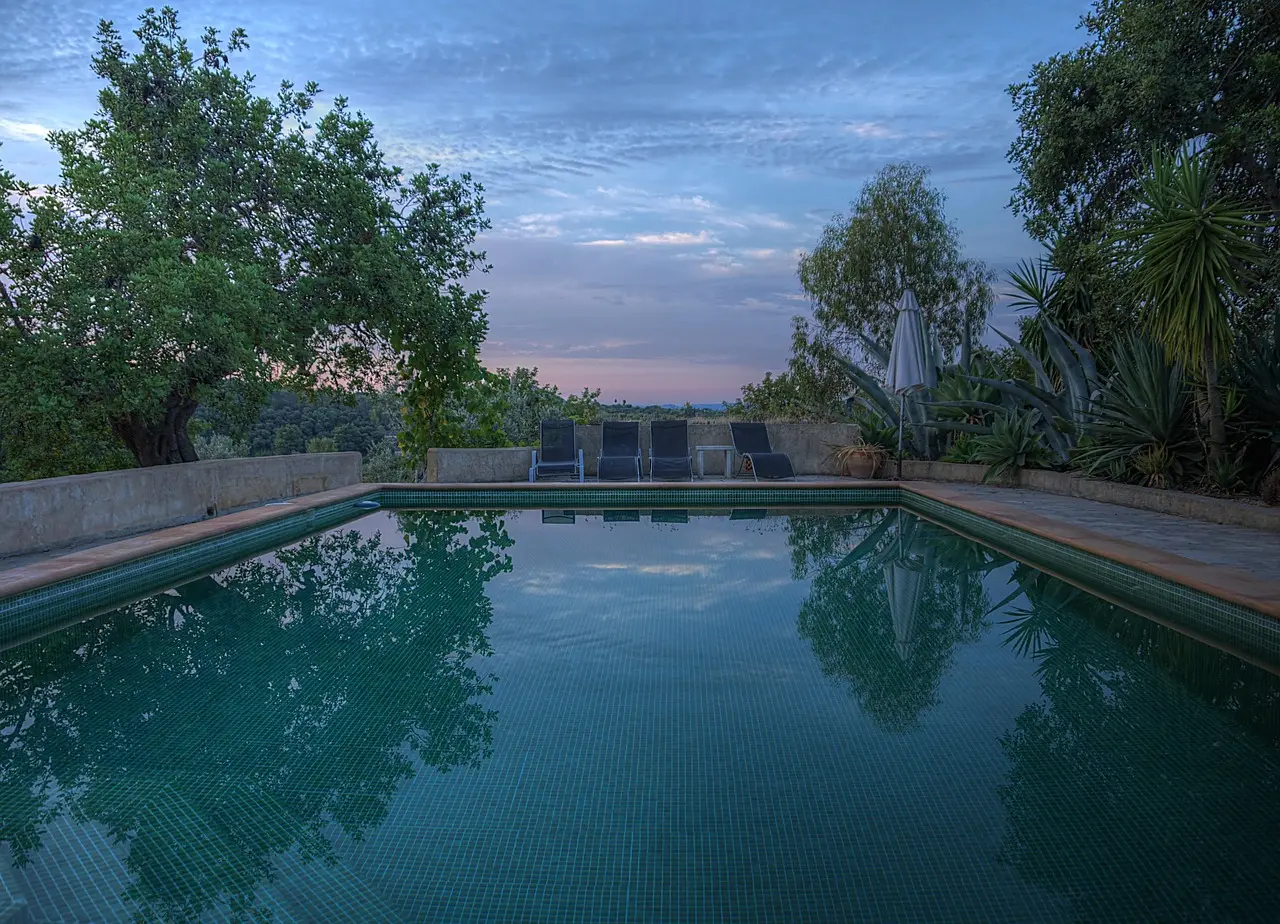 Piscina al anochecer rodeada de vegetación mediterránea